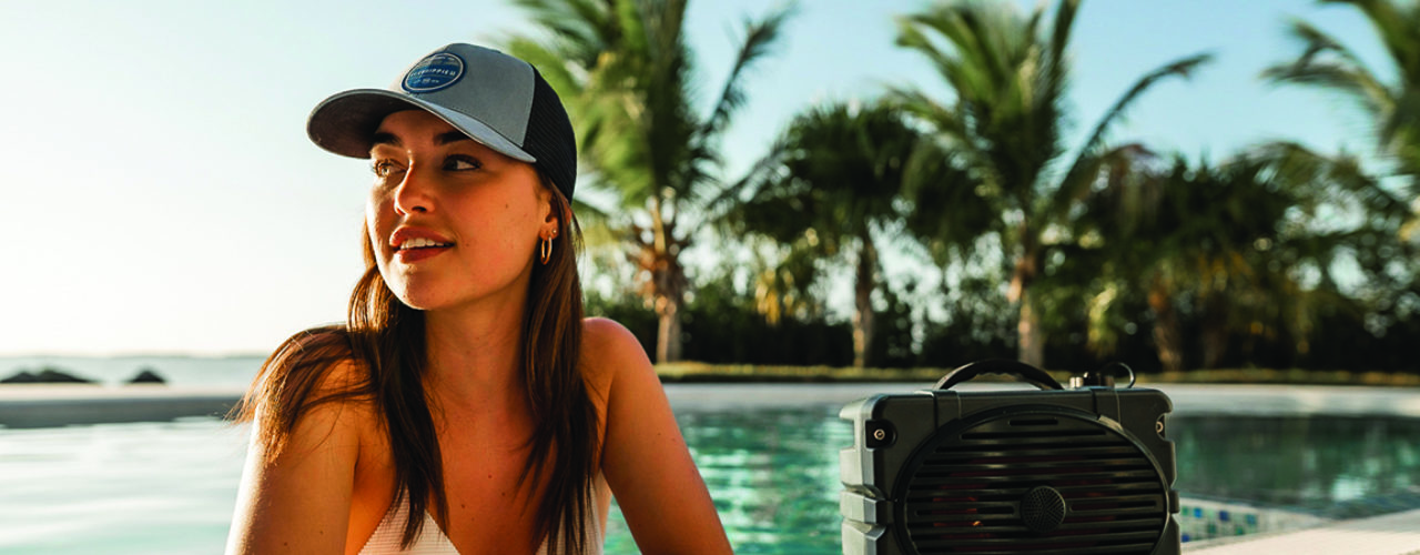 Woman smiling in Fish Hippie cap, next to a pool.