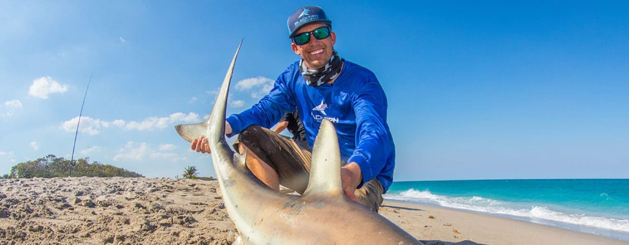 Man smiling at catching a large fish.