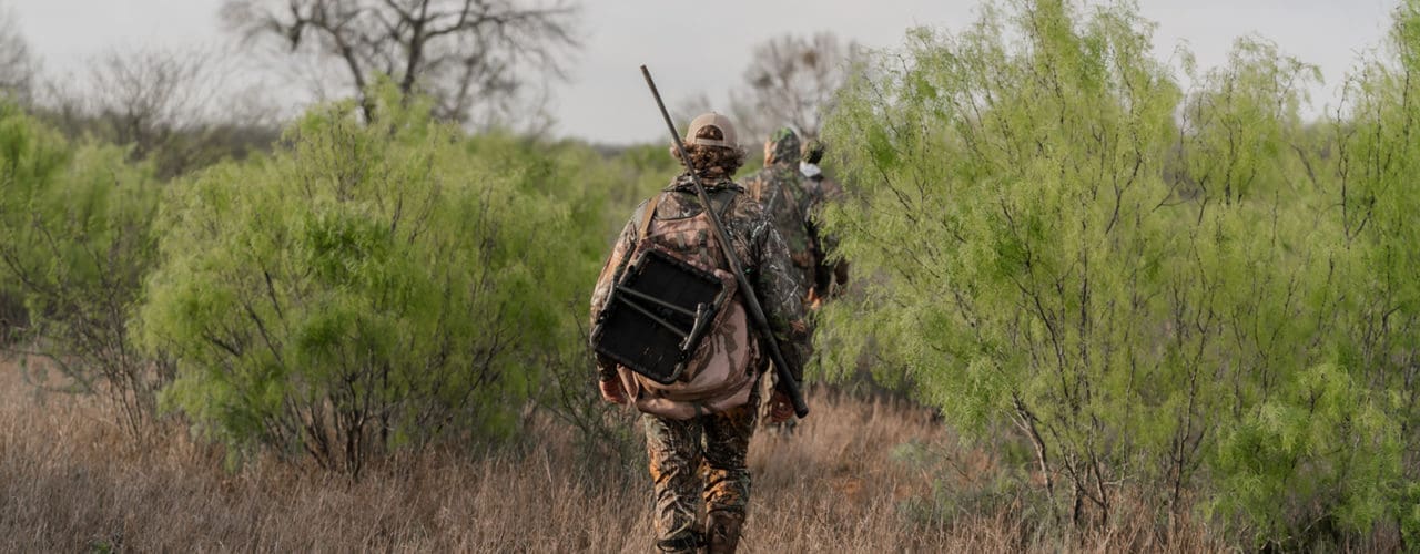 People walking with hunting gear.