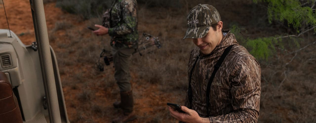 Man in camo smiling at his phone.