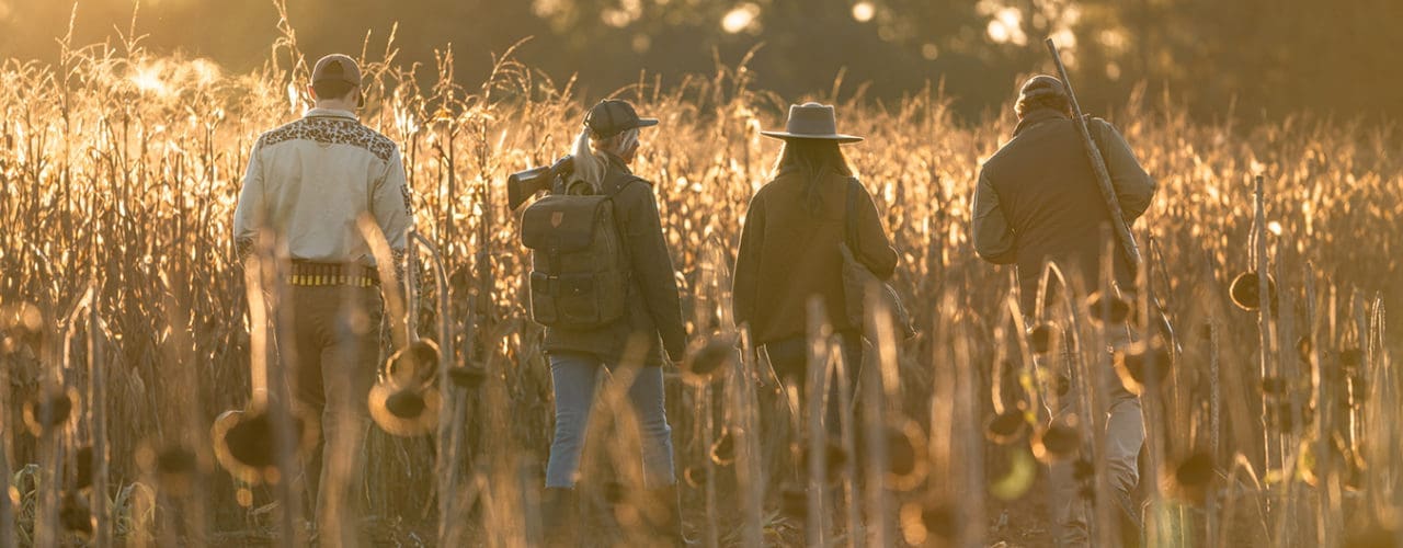 Men and women hunting in field.