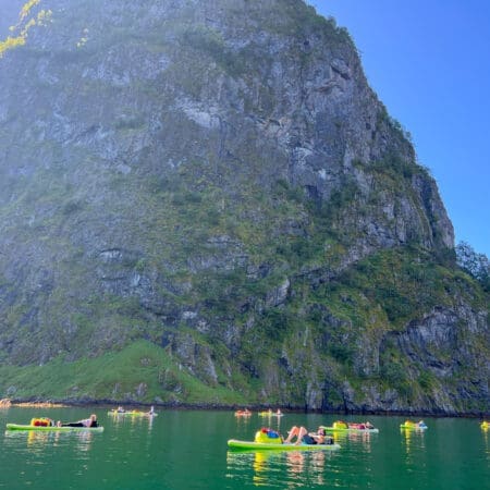 Paddle boarders rest while near a mountain