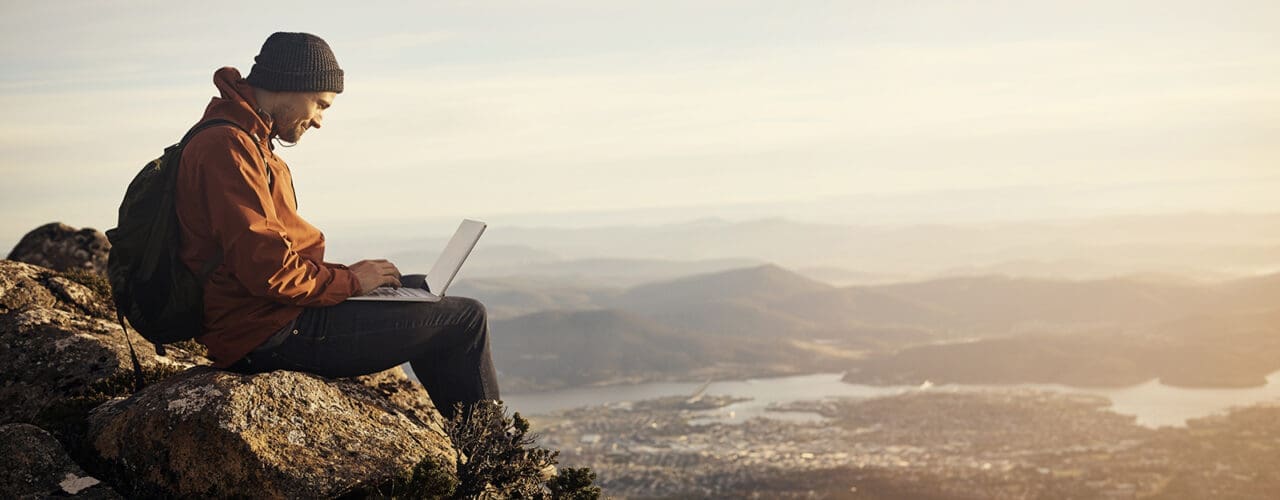 Man using his laptop on top of a mountain